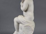 an antique statue of a boy sitting on a rock with his hand on his chin