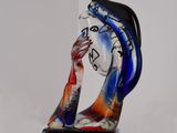une sculpture en verre représentant une femme vêtue d'une robe bleue et rouge