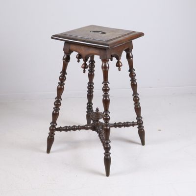 an old wooden table with a small square top on a white floor