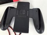 a black nintendo switch controller with a red cord next to it