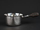 a silver saucepan with a wooden handle on a black background