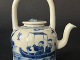 a blue and white teapot with a boat on it