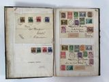 an open book with stamps on it sitting on top of a table