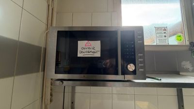 un micro-ondes sur lequel est collé un autocollant, posé sur un plan de travail