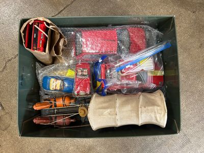 une boîte verte remplie d'objets divers, posée par terre