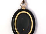 a close up of a black and gold pendant on a white background