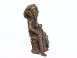 figurine of a woman sitting on a rock holding a baby