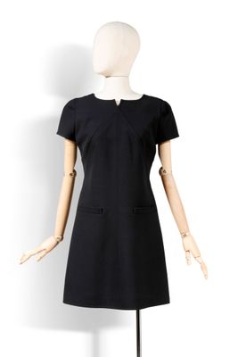 Le mannequin porte une robe noire à col blanc.