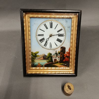 Pendule dans un encadrement en bois noirci et doré en fixé s…