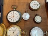 many different types of pocket watches sitting on a table