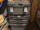 une pile de caisses à outils dans un garage, à côté d'autres outils
