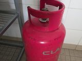 une bouteille de gaz rouge posée par terre à côté d'une étagère