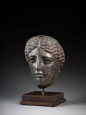a bronze head of a woman on a wooden stand
