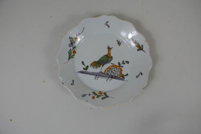 Assiette en faïence polychrome à décor d’oiseau et papillon.