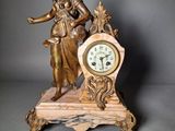 a statue of a woman holding a clock on a table