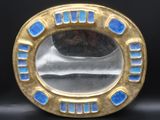 une image montrant un gros plan d'une bague dorée et bleue posée sur une surface noire