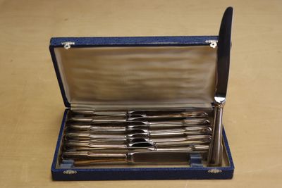 une mallette bleue contenant de l'argenterie, posée sur une table