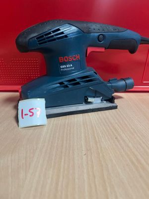 une ponceuse orbitale Bosch posée sur une table en bois, à côté d'une boîte rouge