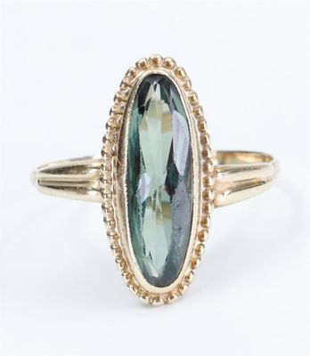 a close up of a gold ring with an oval green tourmaline