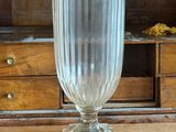 un vase en verre posé sur une table devant une commode