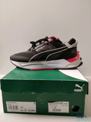 une paire de baskets noires et rouges posée sur une boîte verte