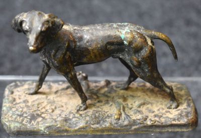 bronze statue of a dog standing on a rock with a black background