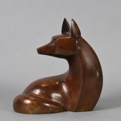 a bronze sculpture of a dog sitting on a gray surface
