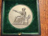 an old silver medal in a green velvet box on a wooden table
