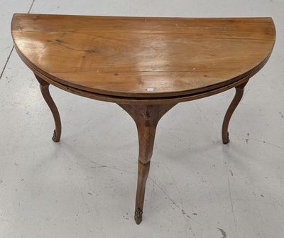 une petite table en bois au plateau incurvé, posée sur un sol blanc
