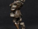 antique bronze figurine of a boy with a dog on a rock