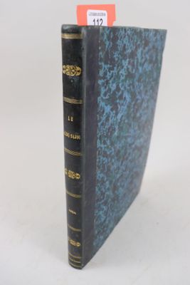 un vieux livre à la couverture bleue posé sur une table blanche
