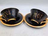 pair of black and gold coffee cups and saucers with i love you written on them