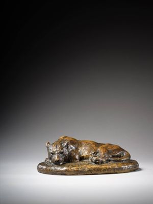 une statue en bronze représentant un chien couché sur un rocher