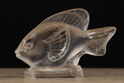 une figurine de poisson en verre transparent posée sur une table en bois