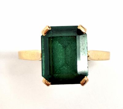 a close up of a ring with a green stone on it