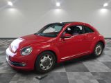 une photo d'une Coccinelle Volkswagen rouge garée sur un sol à damier