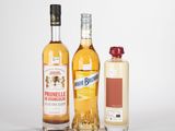 trois bouteilles d'alcool et une bouteille de vin posées sur une surface blanche