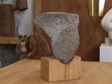 une sculpture en pierre posée sur un bloc de bois, elle-même posé sur une table
