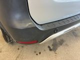 the rear end of a white car with a black bumper