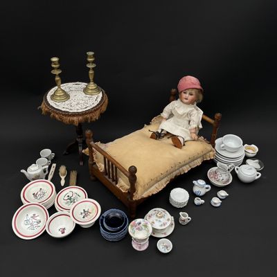 une poupée assise sur un lit, entourée d'autres objets