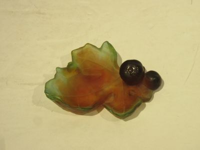 un petit objet en forme de feuille posé sur une surface blanche