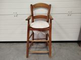 une chaise en bois avec un coussin, posée devant un mur blanc