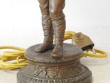 bronze figurine of a man with a hat and boots standing on a pedestal