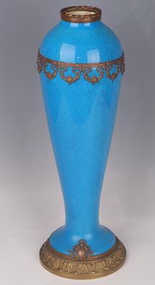 a blue vase sitting on a table with a gold rim