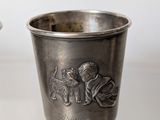 two silver cups that are sitting on a table