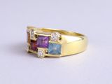 an image of a close up of a yellow gold ring with three different colored stones