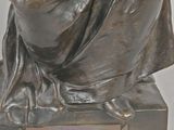 statue of a woman sitting on top of a wooden base