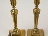 pair of brass candlesticks on a white background with a silver ashtray