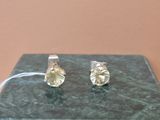 une paire de boucles d'oreilles à clous en diamant jaune posée sur une table en marbre