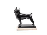 une statue noire représentant un chien debout sur un socle en bois